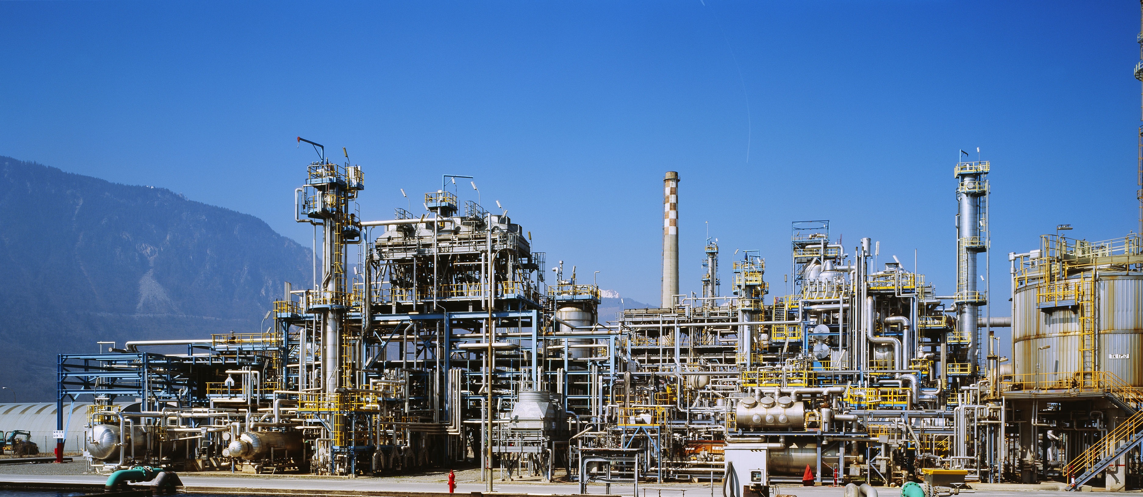 Oil refinery process units against mountain backdrop — relocation case